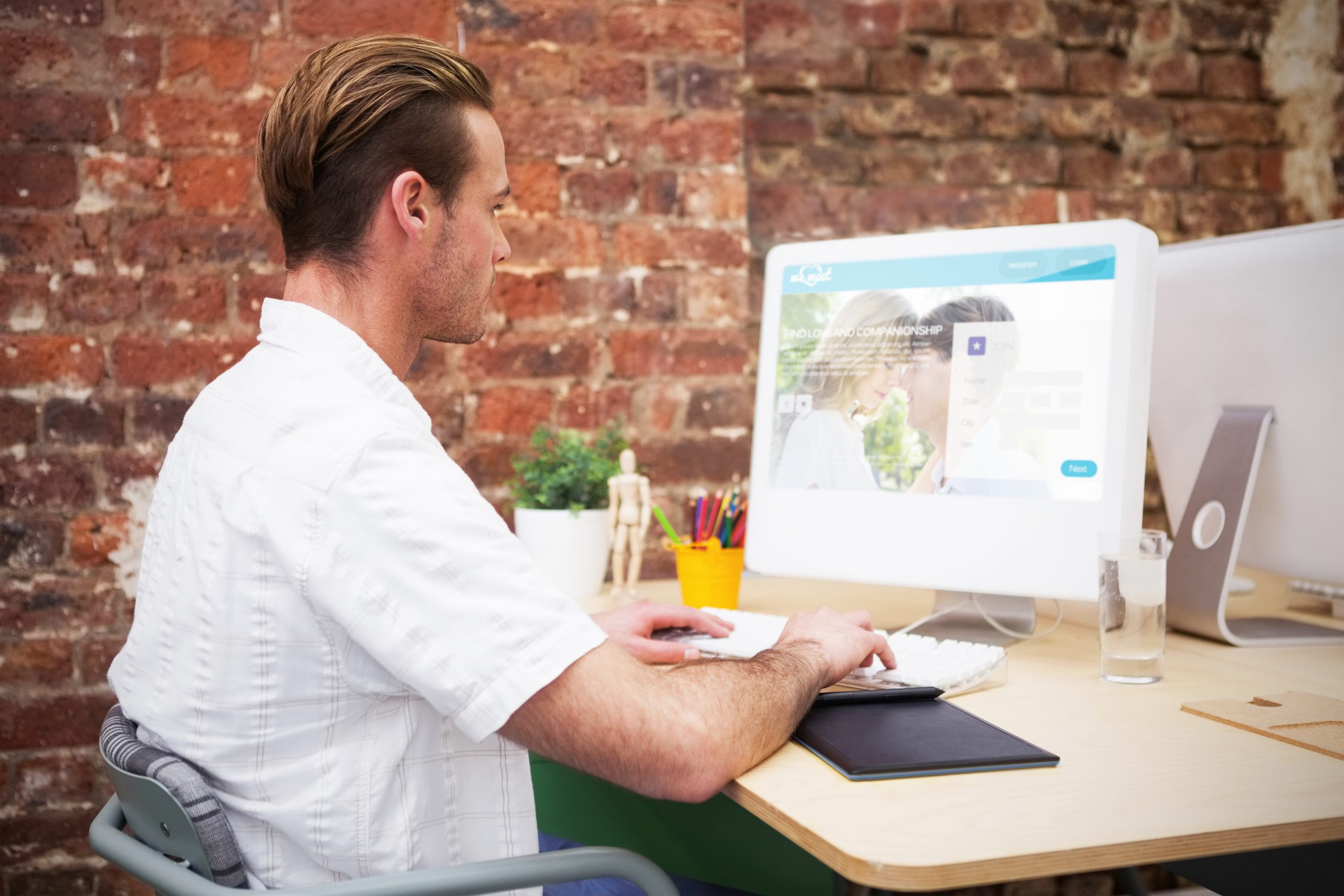 Dating website against creative worker typing on laptop at his desk